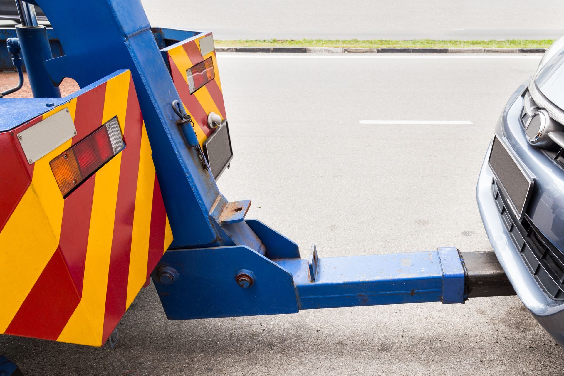 A tow truck is towing a car on the side of the road.