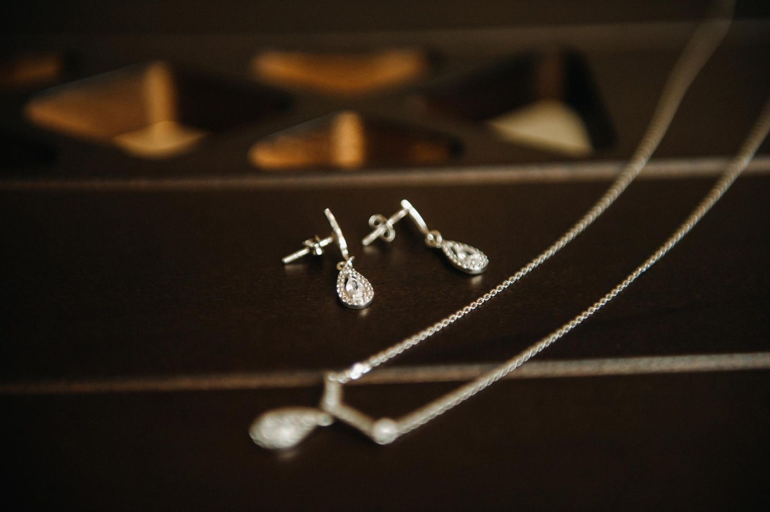 A matching silver necklace and earring set with teardrop pendants rests on a dark, polished wooden surface.