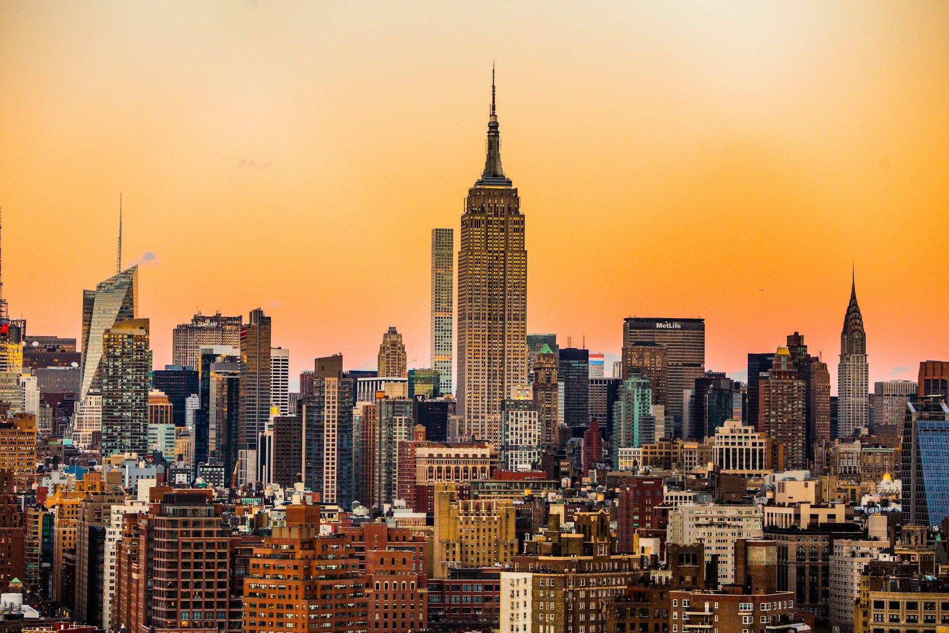 The Empire State Building stands prominently in the center of the New York City skyline at golden hour.