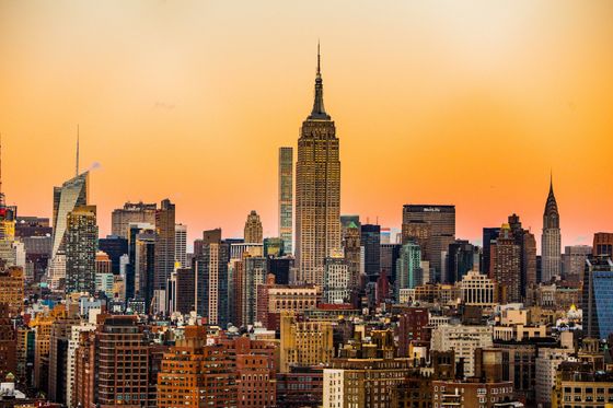 The Empire State Building stands prominently in the center of the New York City skyline at golden hour.