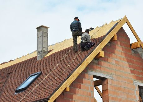 two men are working on the roof of a house