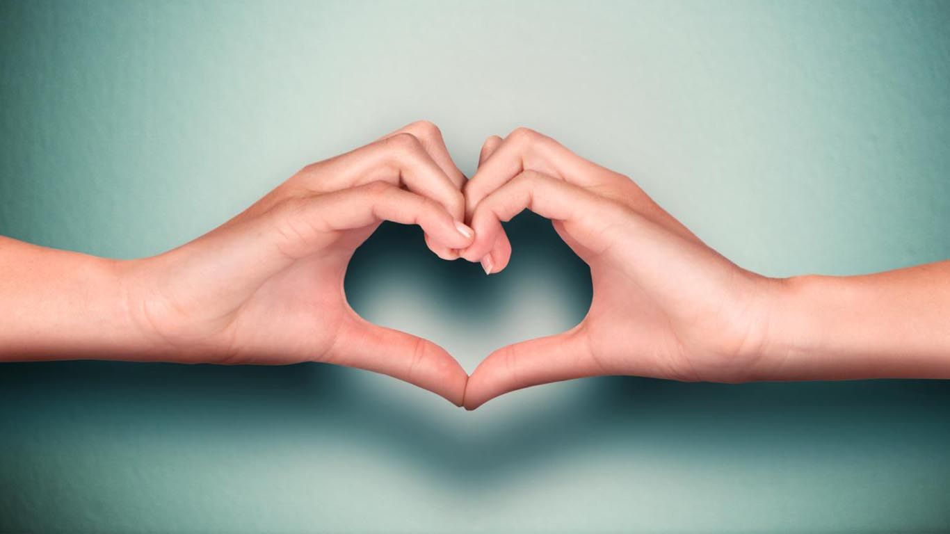 Two hands are making a heart shape with their fingers.