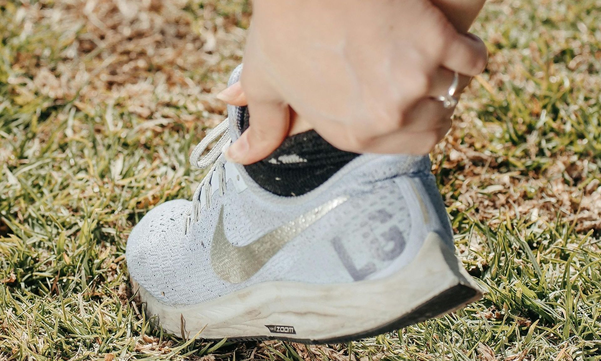 A person is on their sprained anckle on a grassy field.
