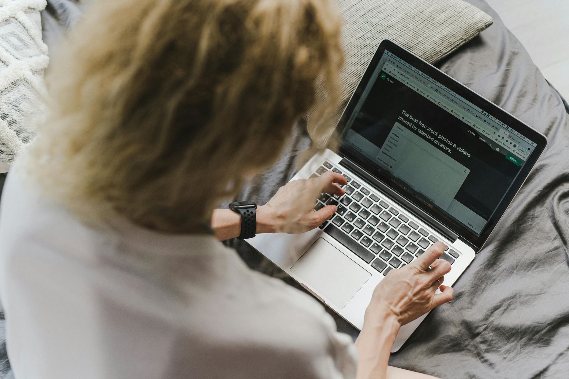 A woman is sitting on a bed using a laptop computer.