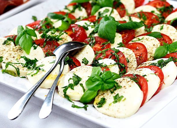 A white plate topped with sliced mozzarella, tomatoes and basil