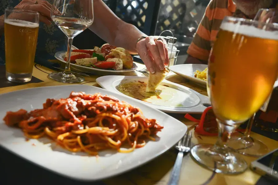 A plate of spaghetti and a glass of beer on a table