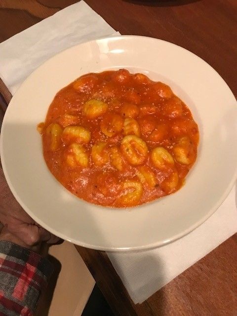 A bowl of gnocchi with tomato sauce on a table