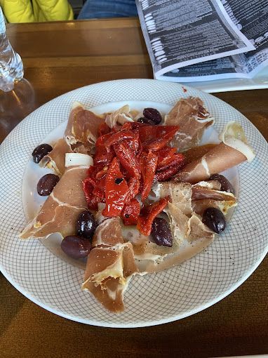 A plate of food with meat, olives and peppers on a table
