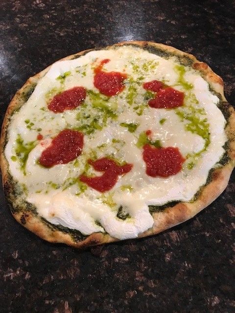 A pesto ricotta pizza sitting on a counter