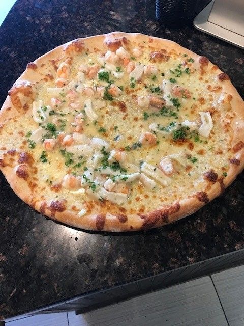 A seafood pizza sitting on a counter