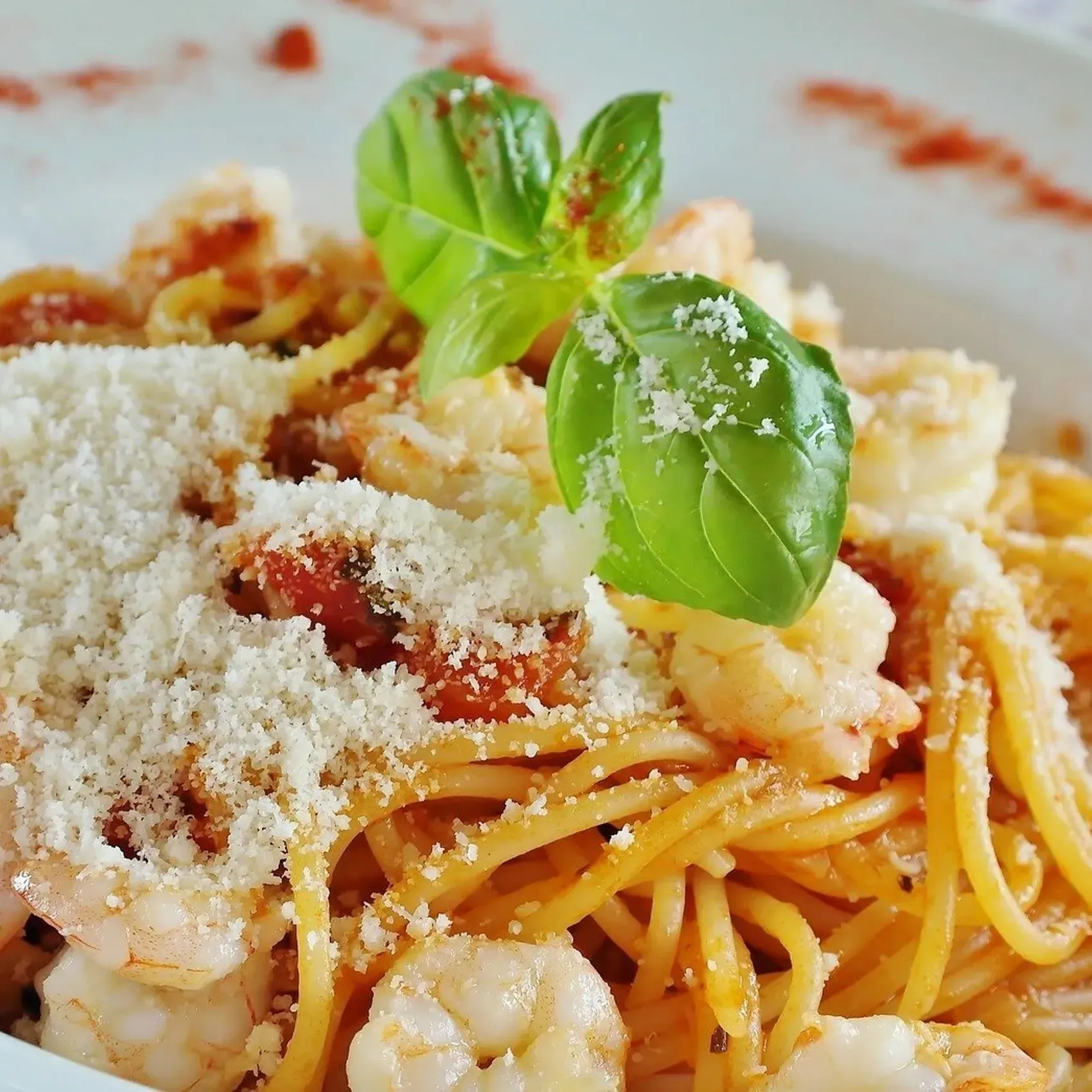 A close up of a plate of spaghetti with shrimp and basil