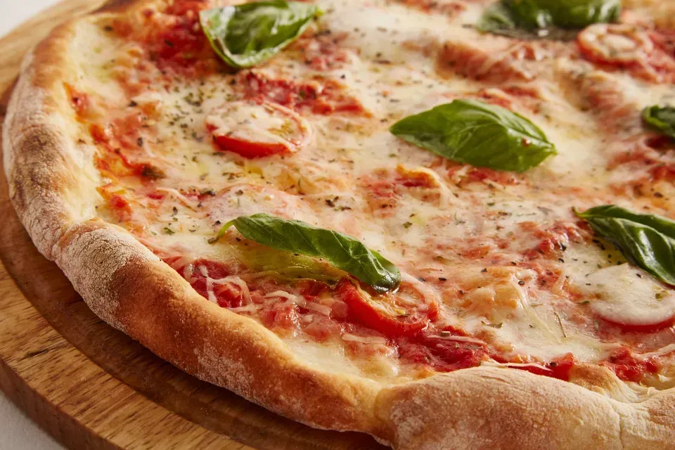 A cheese pizza with basil on a wooden board