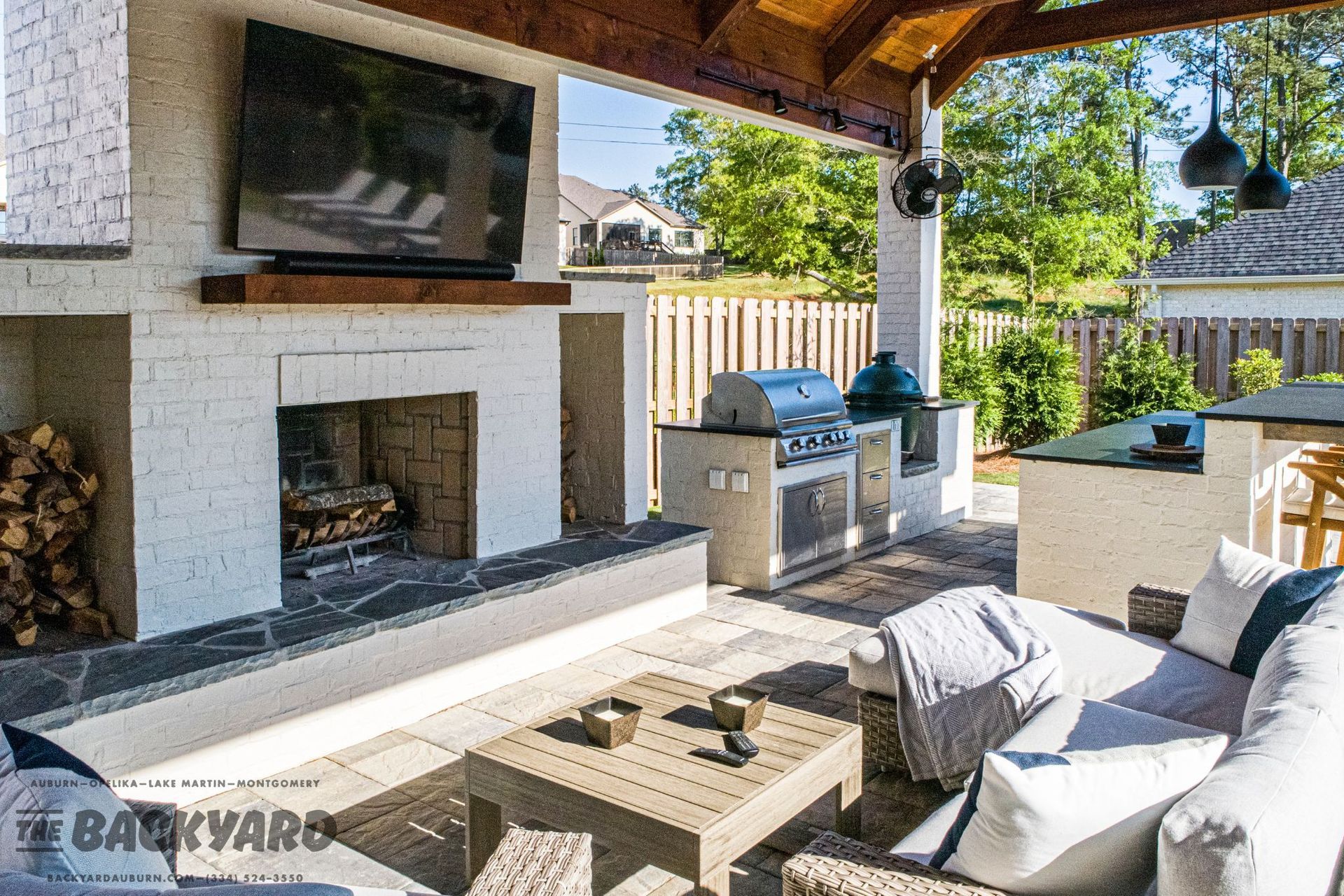 Outdoor patio with fireplace, grill, seating, and a TV.