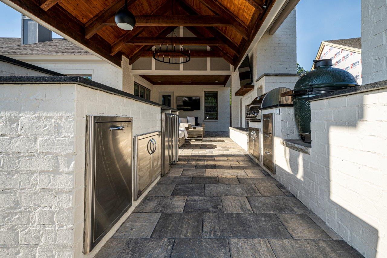 A walkway leading to a large outdoor kitchen with stainless steel appliances.
