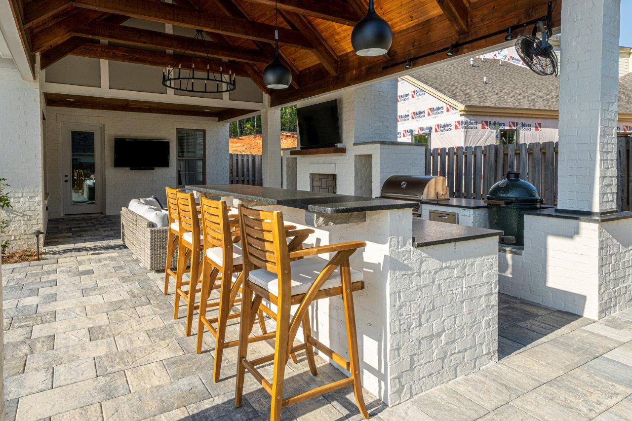 A patio with a bar and stools under a canopy.
