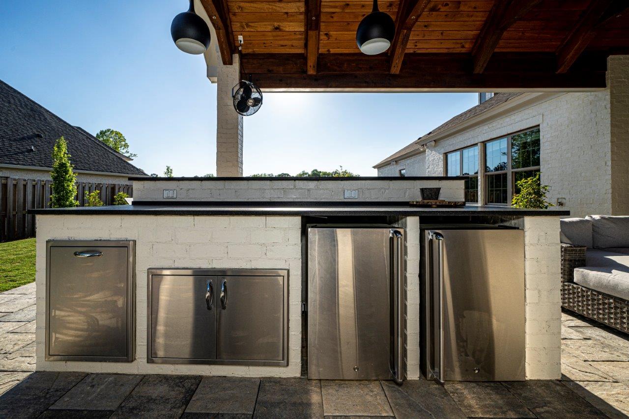 A large outdoor kitchen with stainless steel cabinets and a refrigerator.