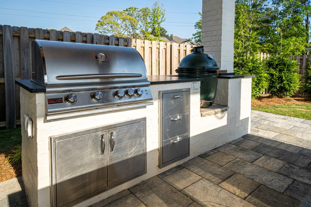 A stainless steel grill is sitting on top of a brick patio.