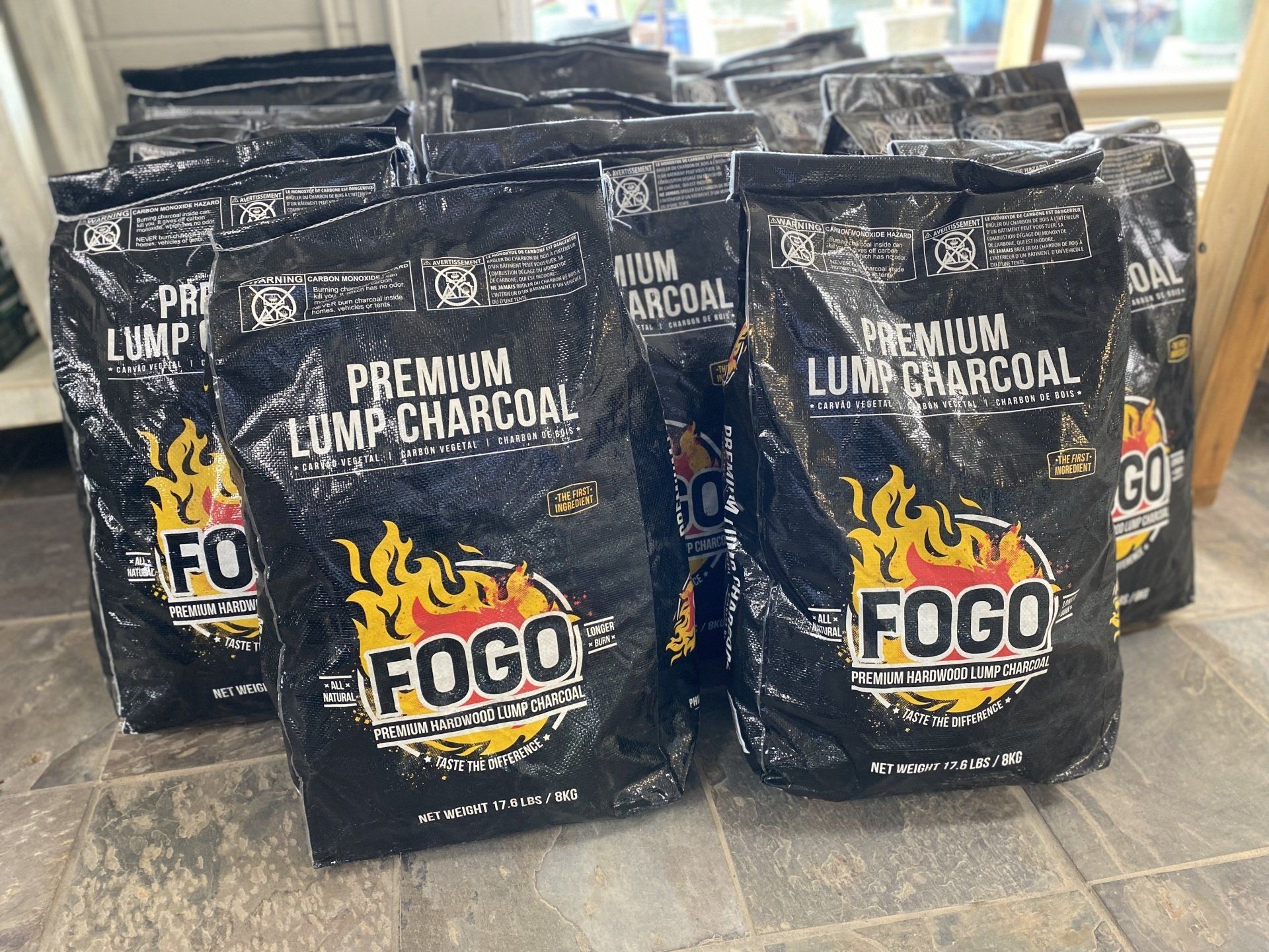 A bunch of bags of fogo premium lump charcoal are sitting on the floor.