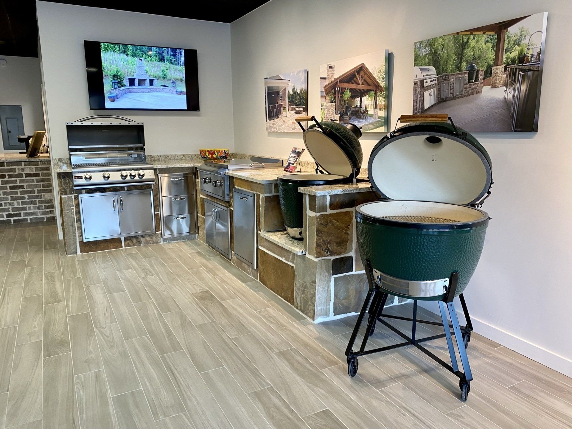 Indoor showroom with outdoor grills and a TV displaying landscape scenes.