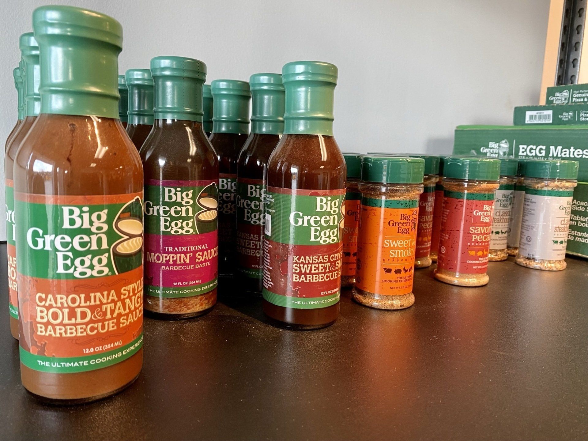 Bottles of Big Green Egg BBQ sauces and spice rubs on a shelf.