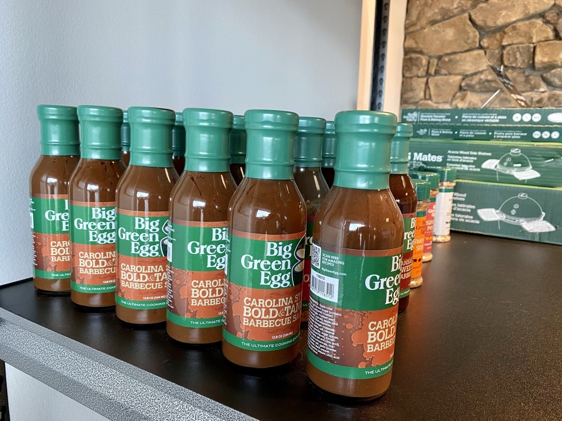 Bottles of Big Green Egg Carolina Bold Barbecue Sauce with green caps on a shelf.