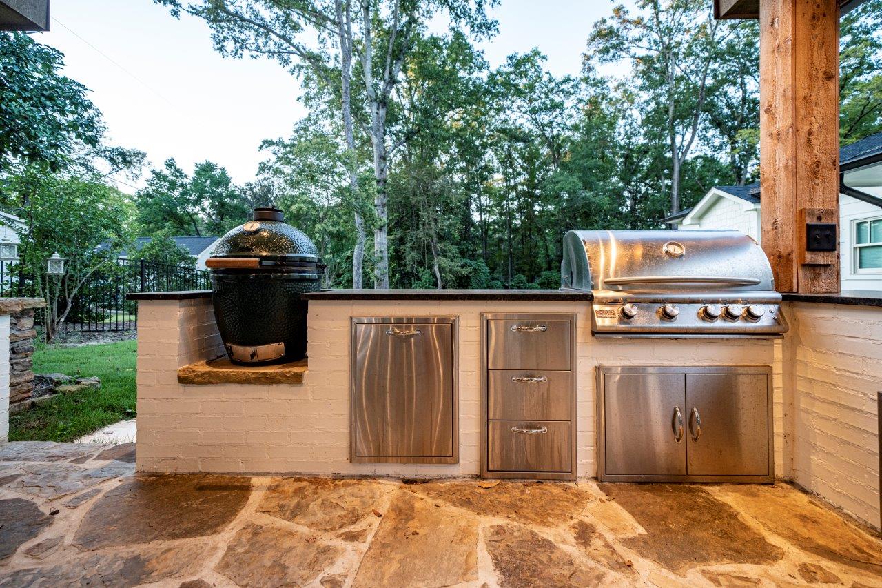 An outdoor kitchen with stainless steel appliances and a grill.