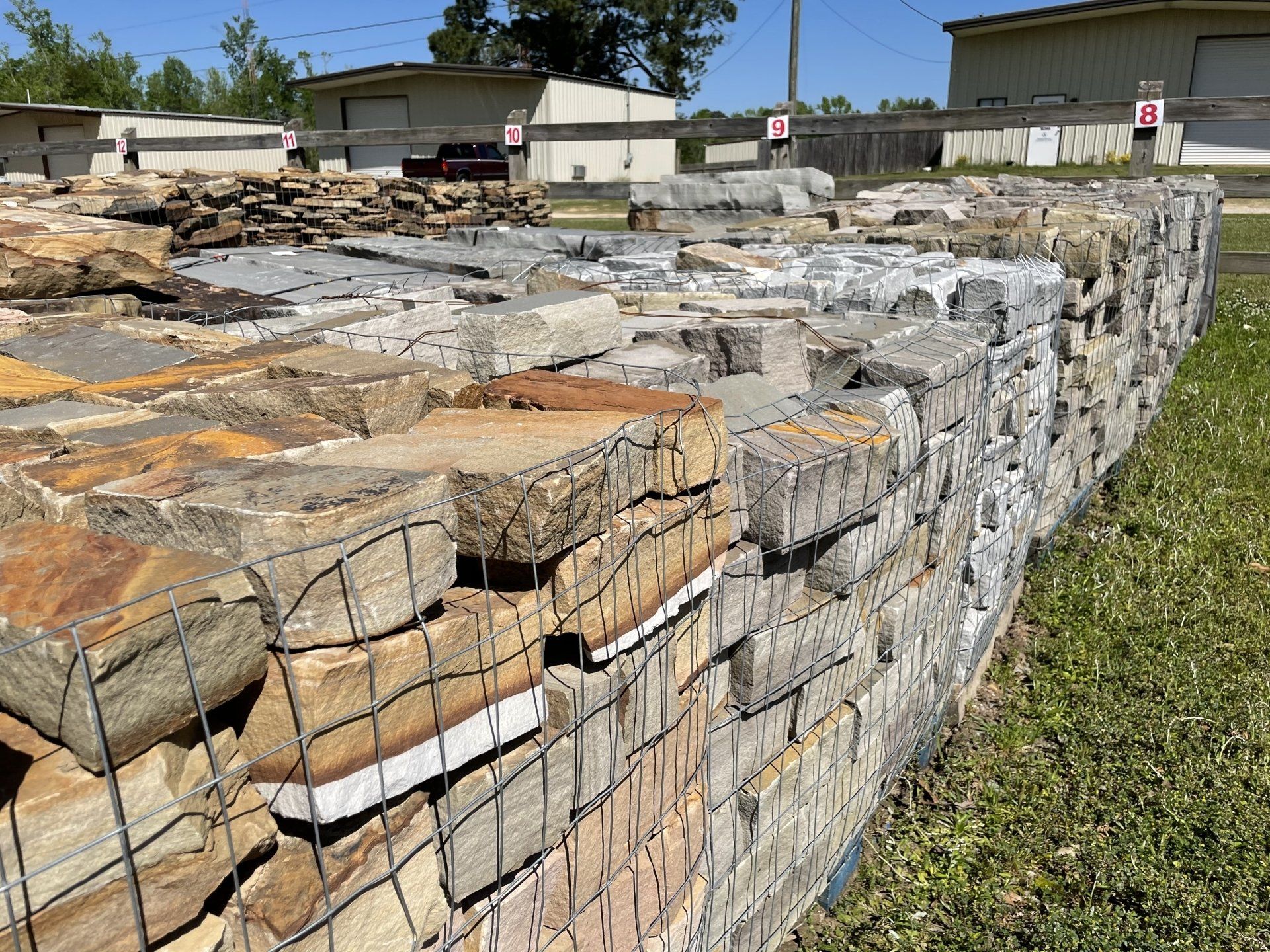 Stone building materials stacked and bound in wire cages, outdoors.