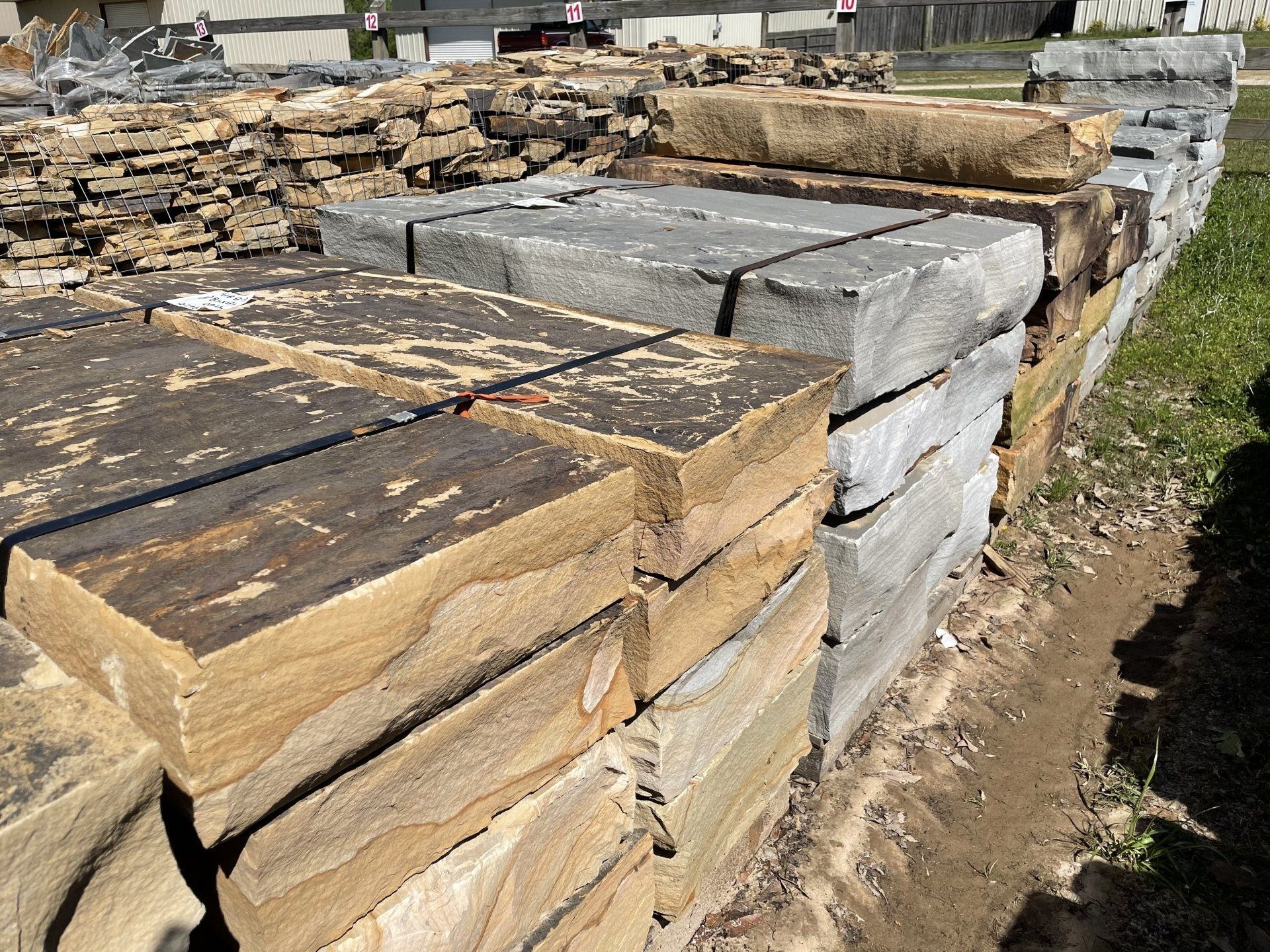 Stacks of rectangular stone blocks in varying colors, outdoors.