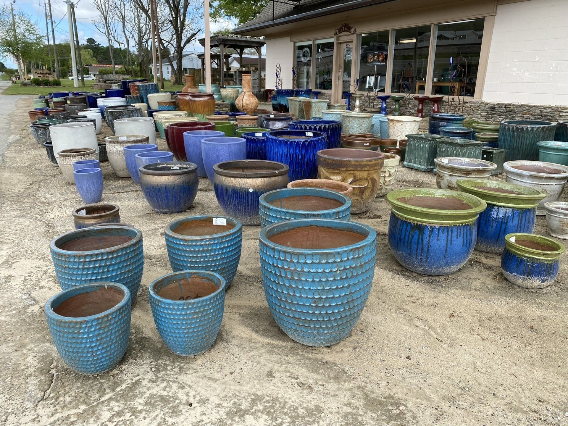 Large assortment of colorful ceramic pots for sale outside a garden store.