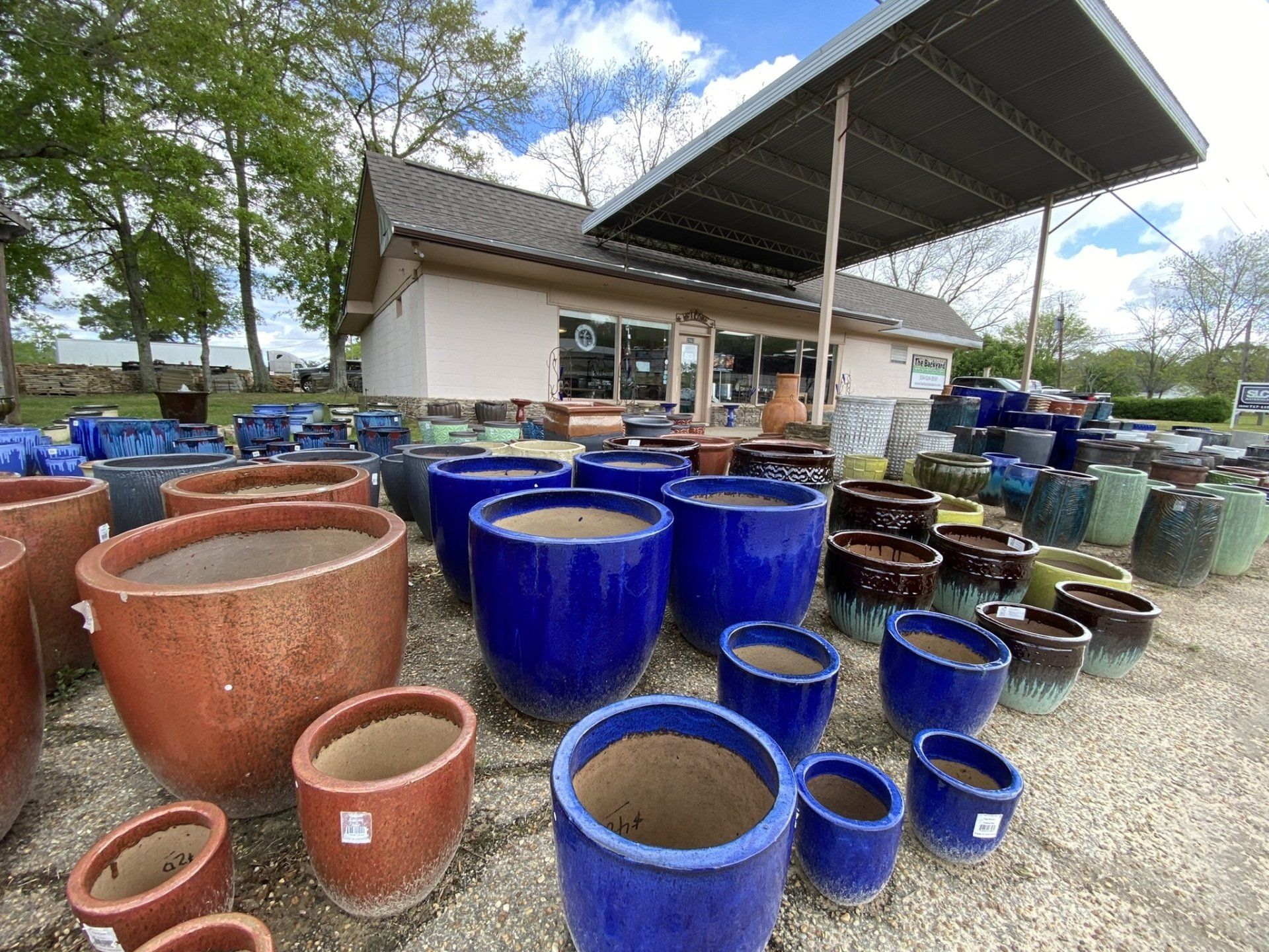 A variety of colorful ceramic pots displayed outside a garden center on a sunny day.