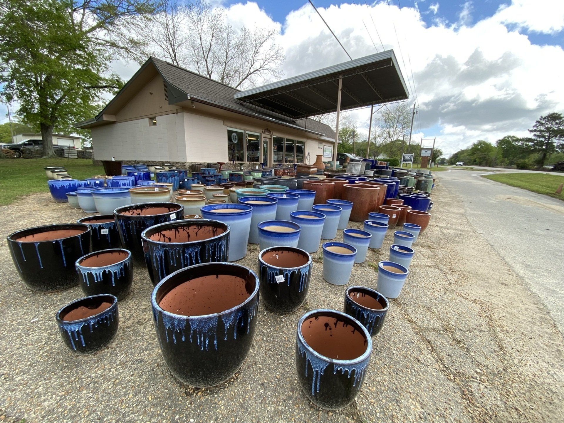 Outdoor plant pots in various colors and sizes displayed outside a store.