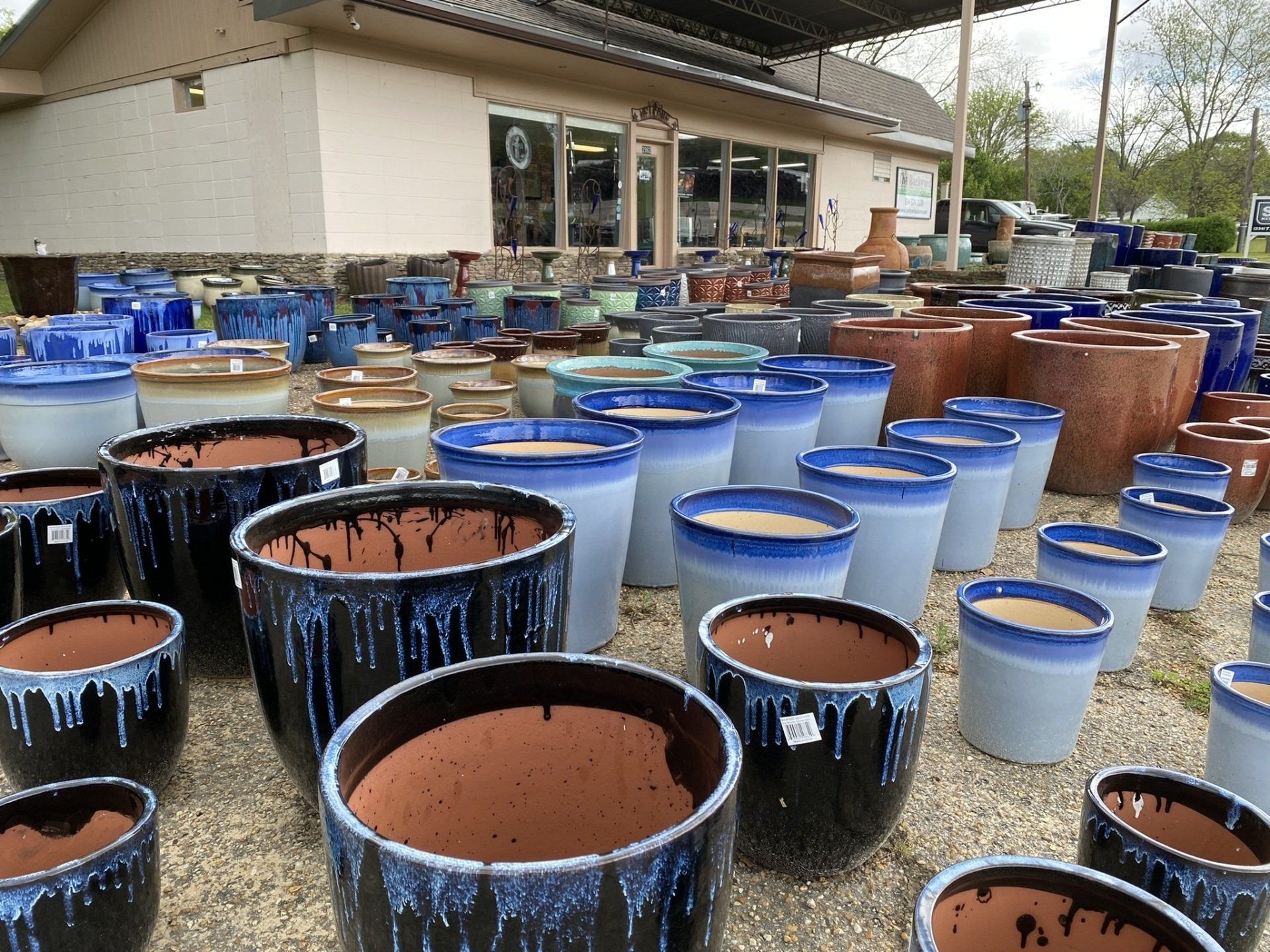 Rows of blue and brown glazed ceramic pots in front of a light-colored building.