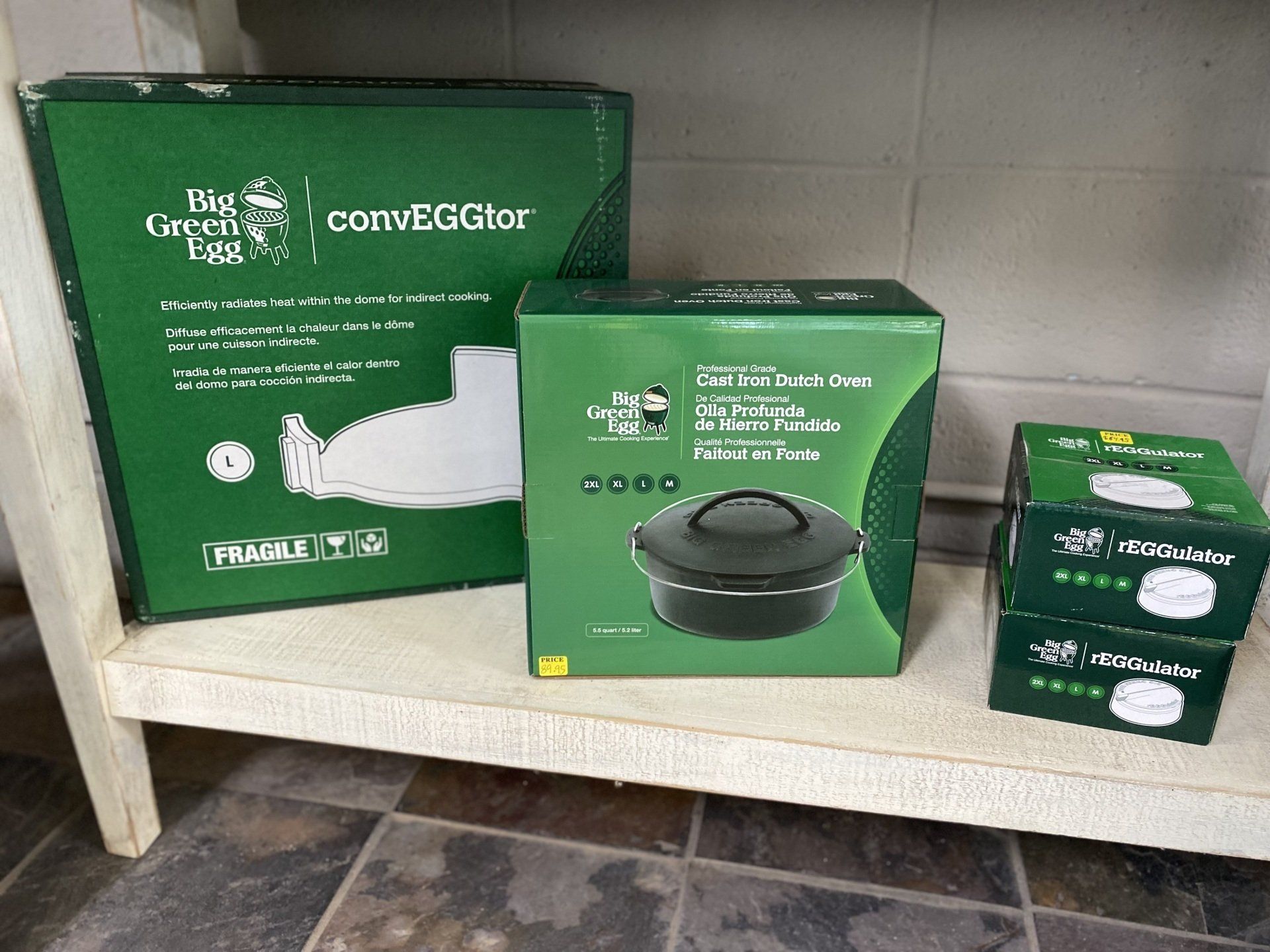 Boxes of Big Green Egg cooking accessories on a shelf.