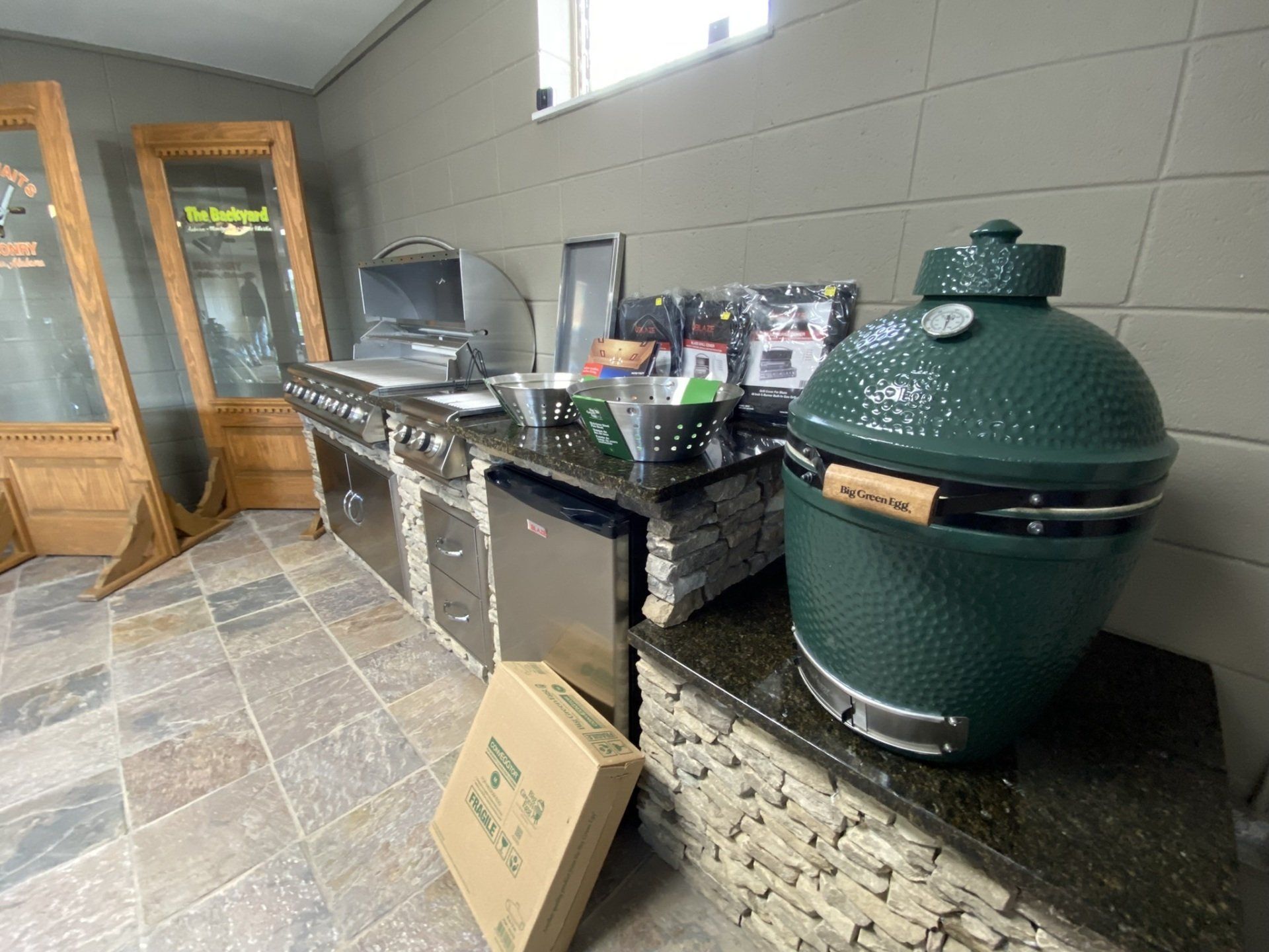 A showroom with outdoor kitchen setup, including a large green Big Green Egg grill.