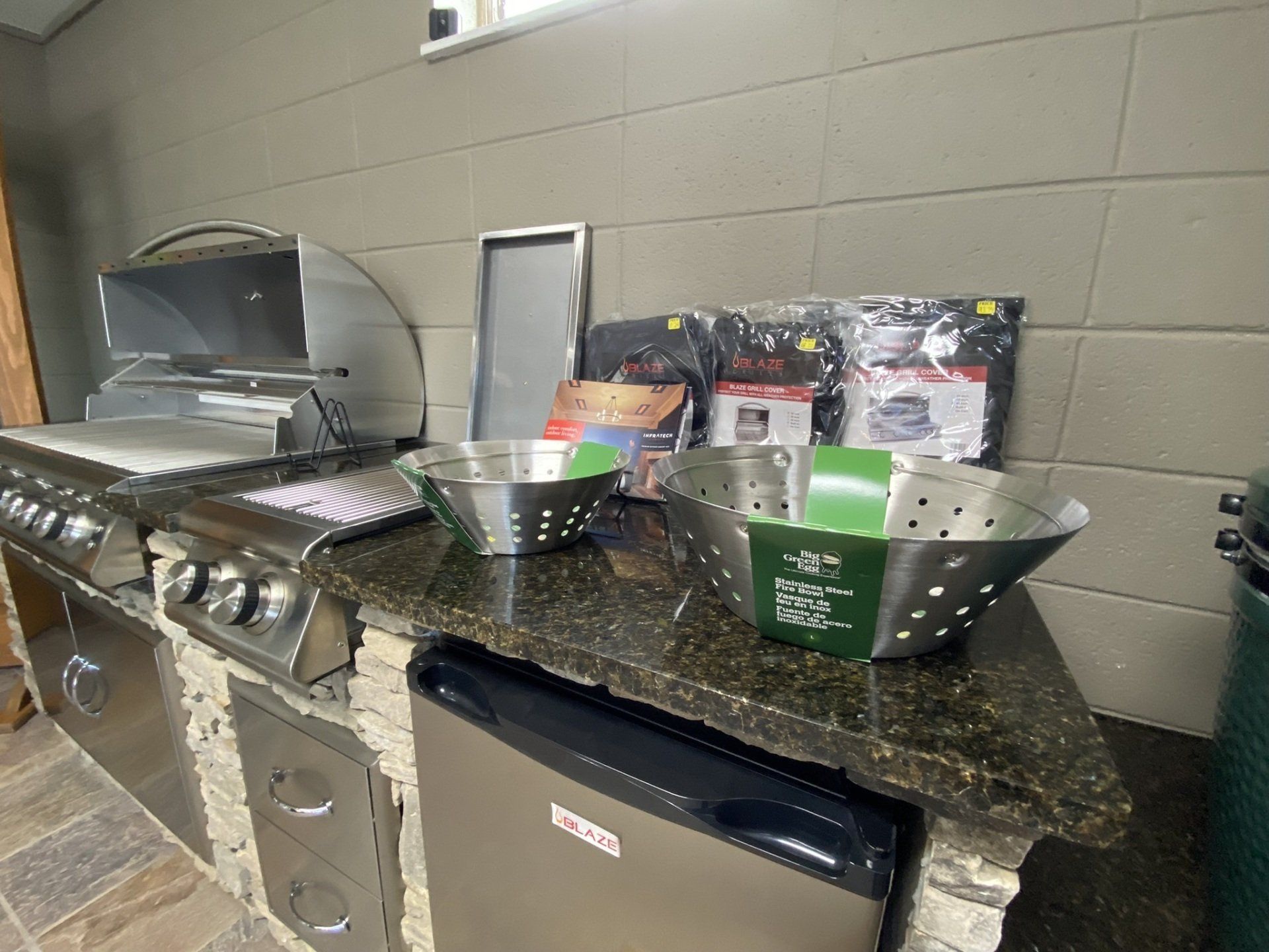 Outdoor kitchen with grill, charcoal, and accessories on a granite countertop.