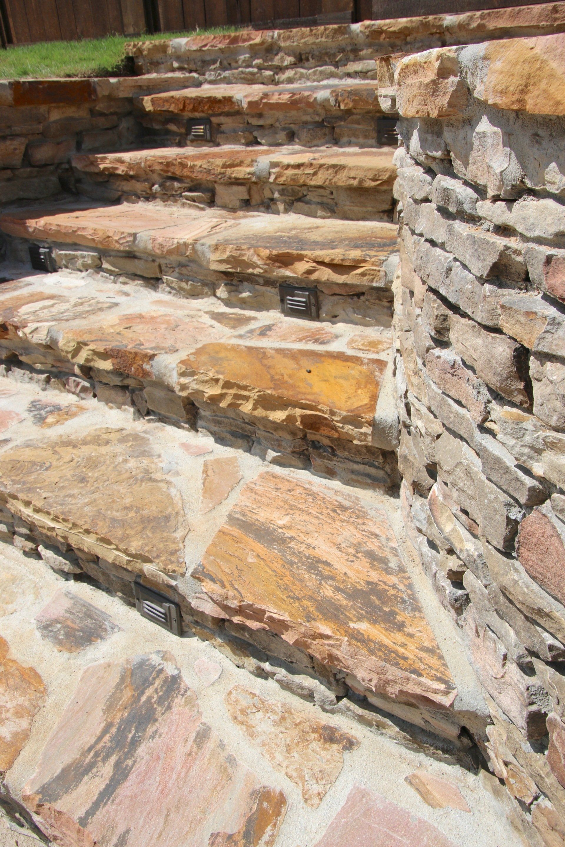 Stone steps leading up, with a curved stone wall on the side, outdoors.