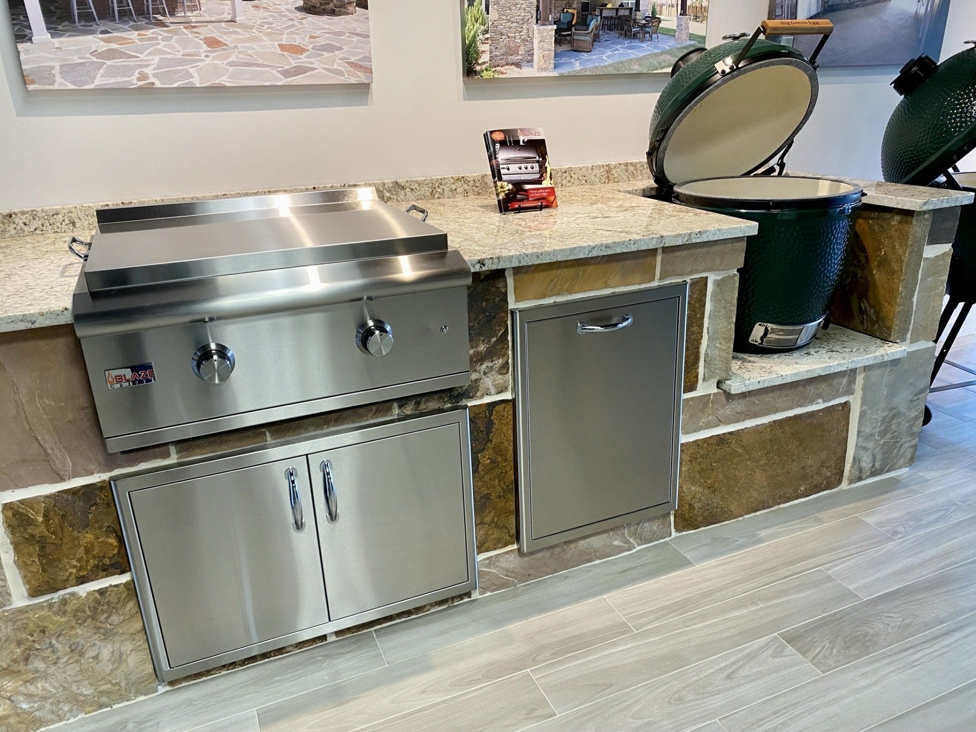 Outdoor kitchen setup with a stainless steel grill, Big Green Egg, and stone facade.