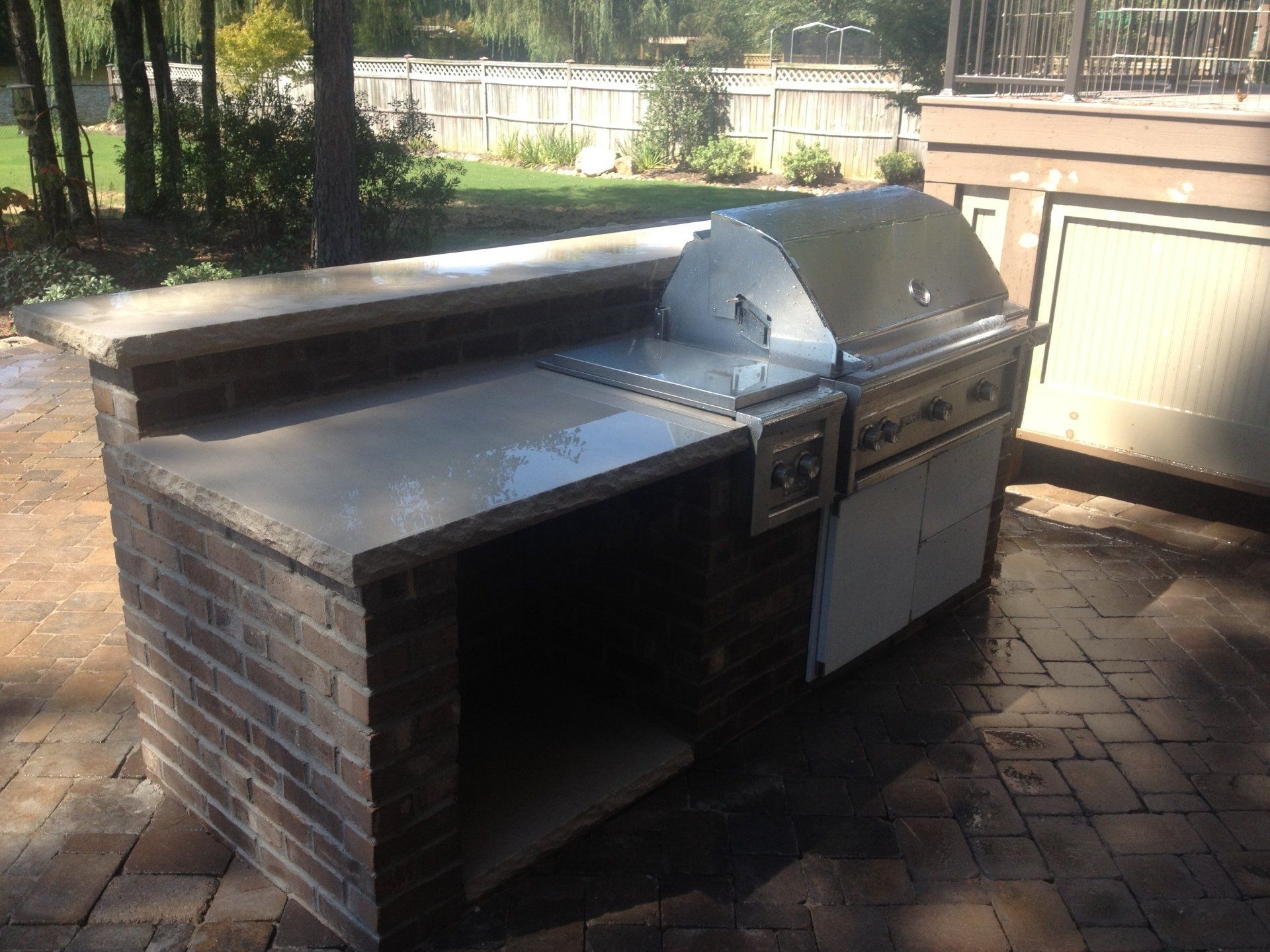 An outdoor kitchen with a grill and a brick counter top