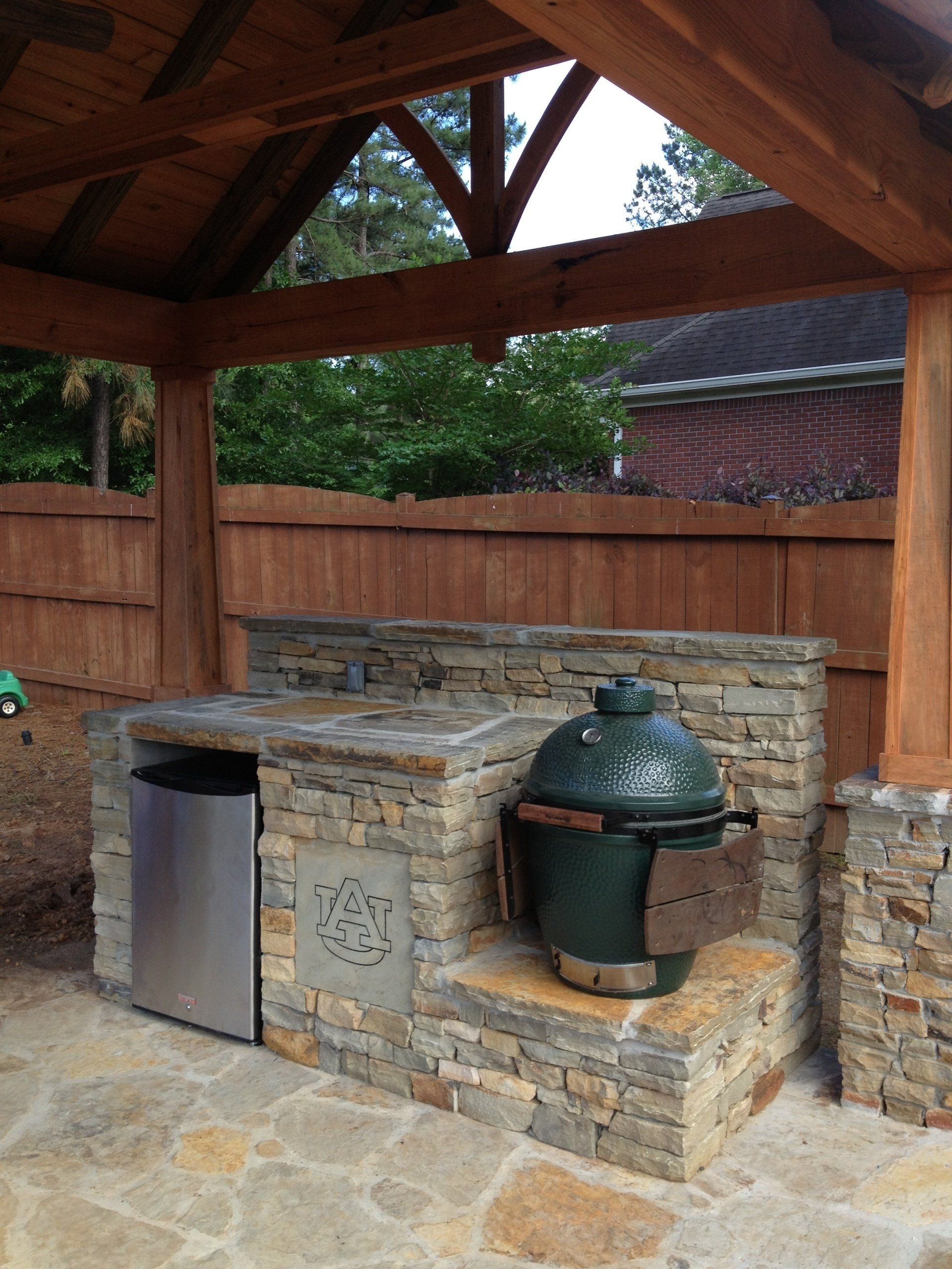 A green egg is sitting on a stone counter under a wooden structure