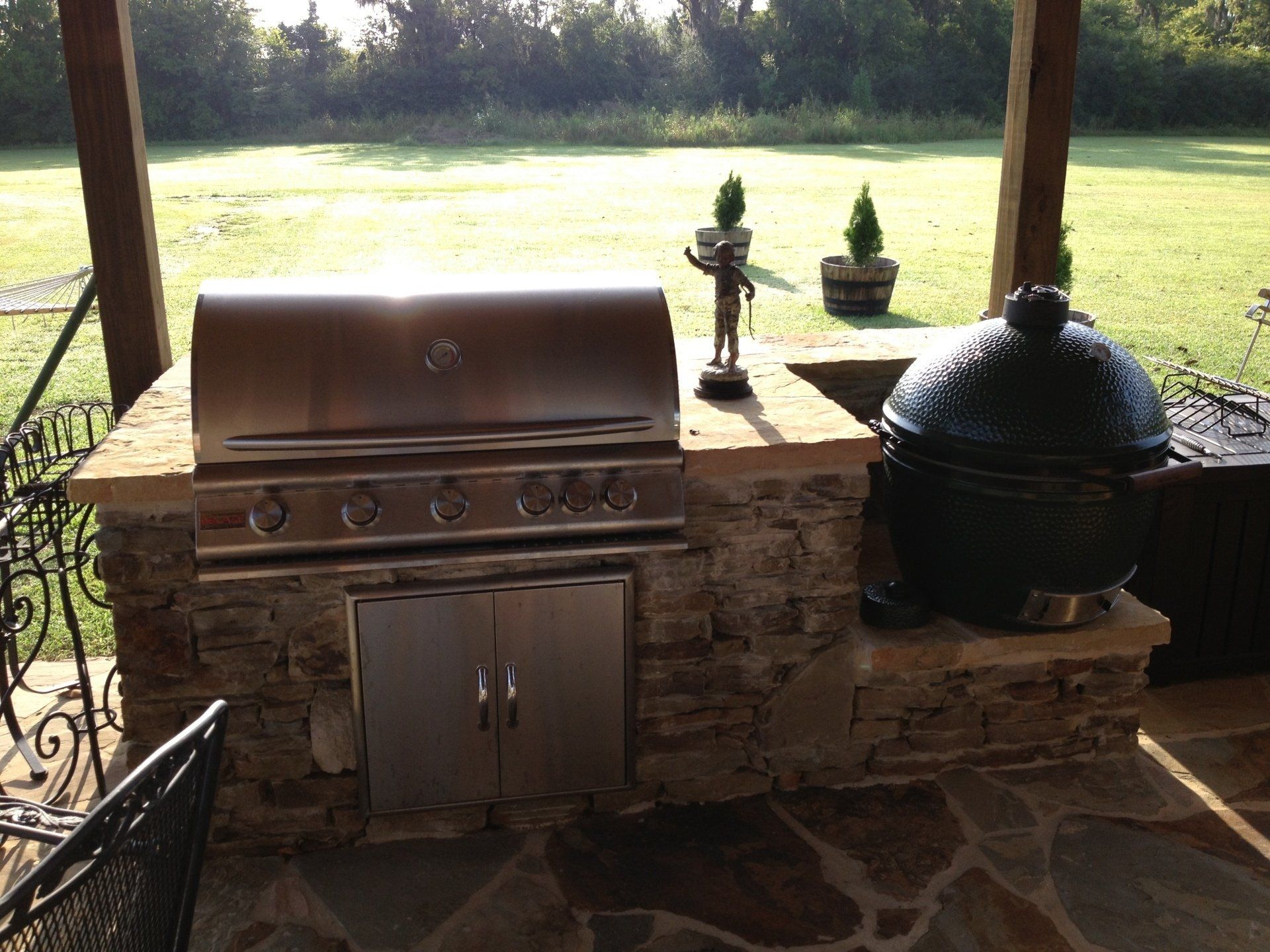 An outdoor kitchen with a grill and a big green egg