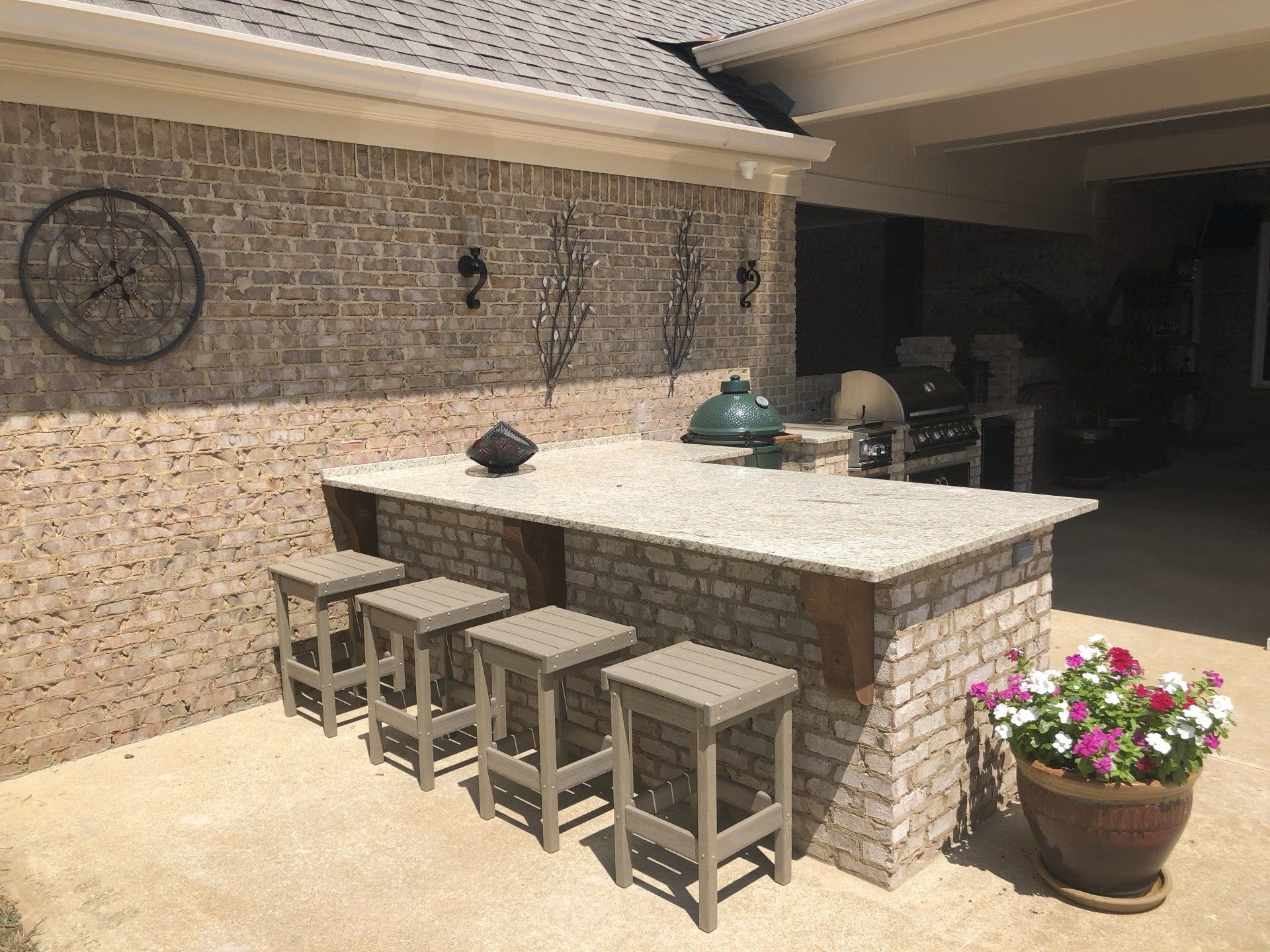 A patio with a brick wall , a table and stools.