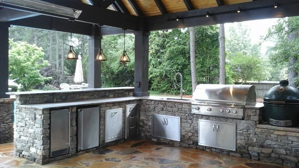 A large outdoor kitchen with a grill , sink , and refrigerator.