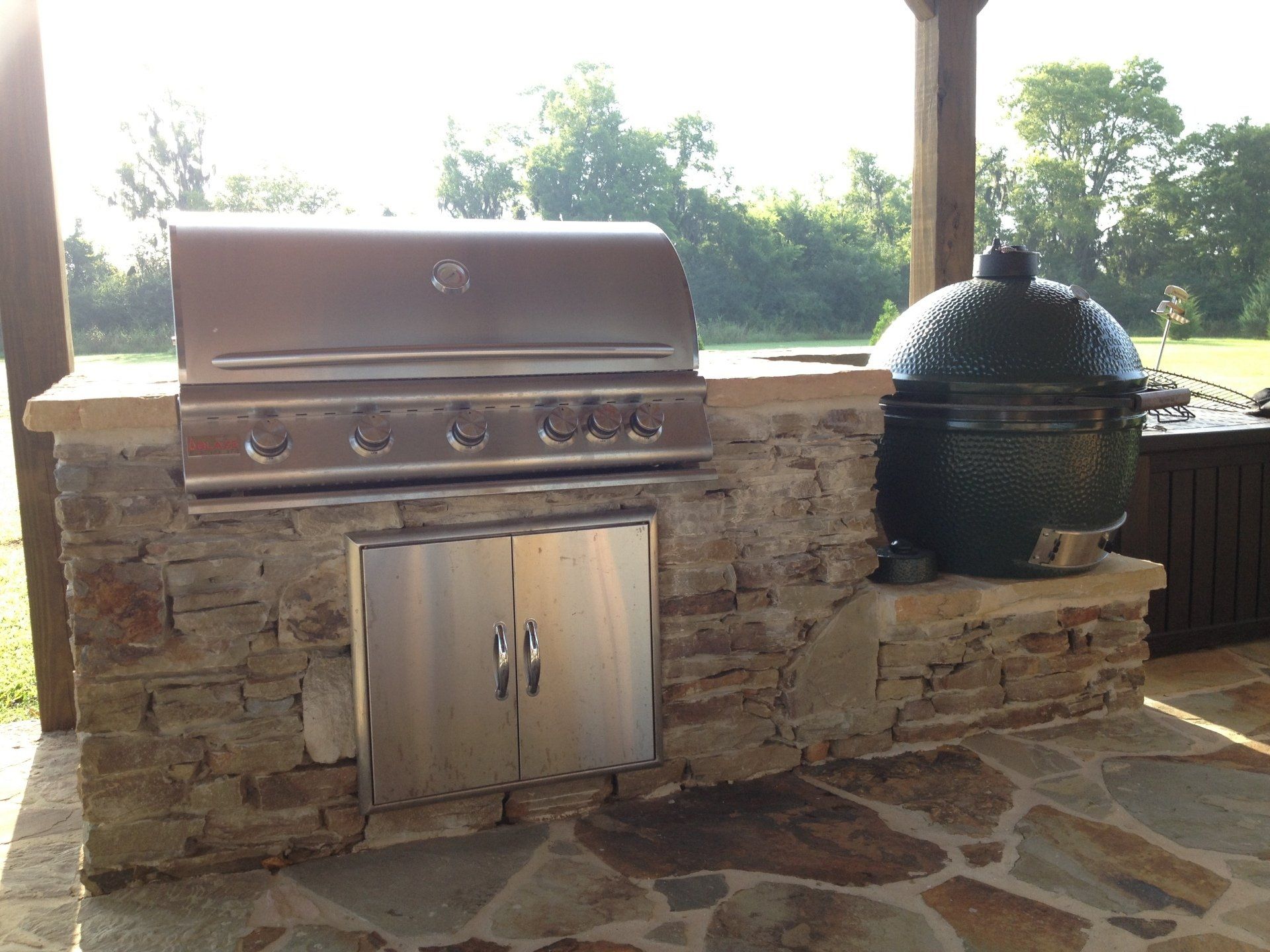 A stainless steel grill is built into a stone wall.
