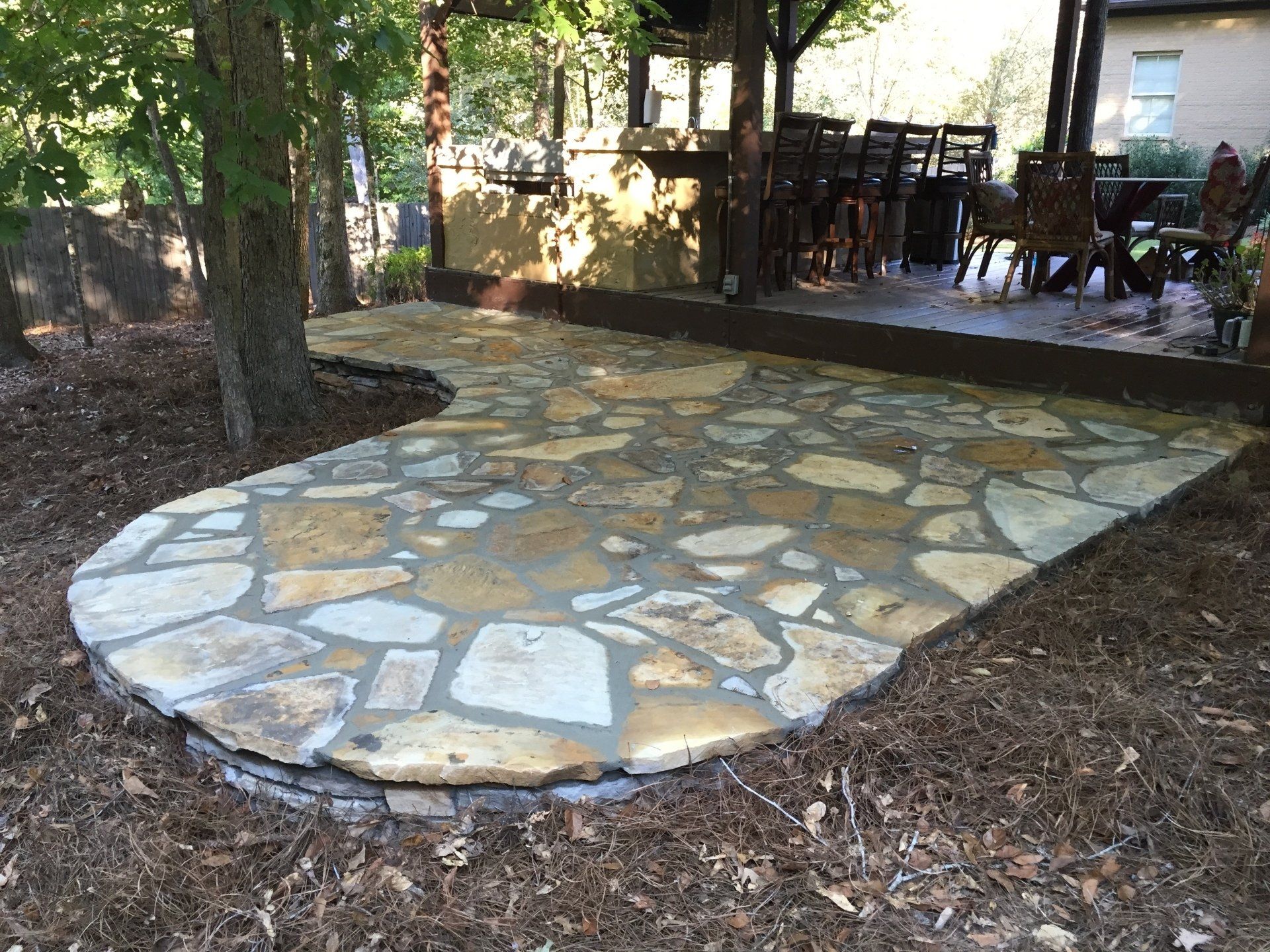 Stone patio with curved edge, next to a covered outdoor dining area.