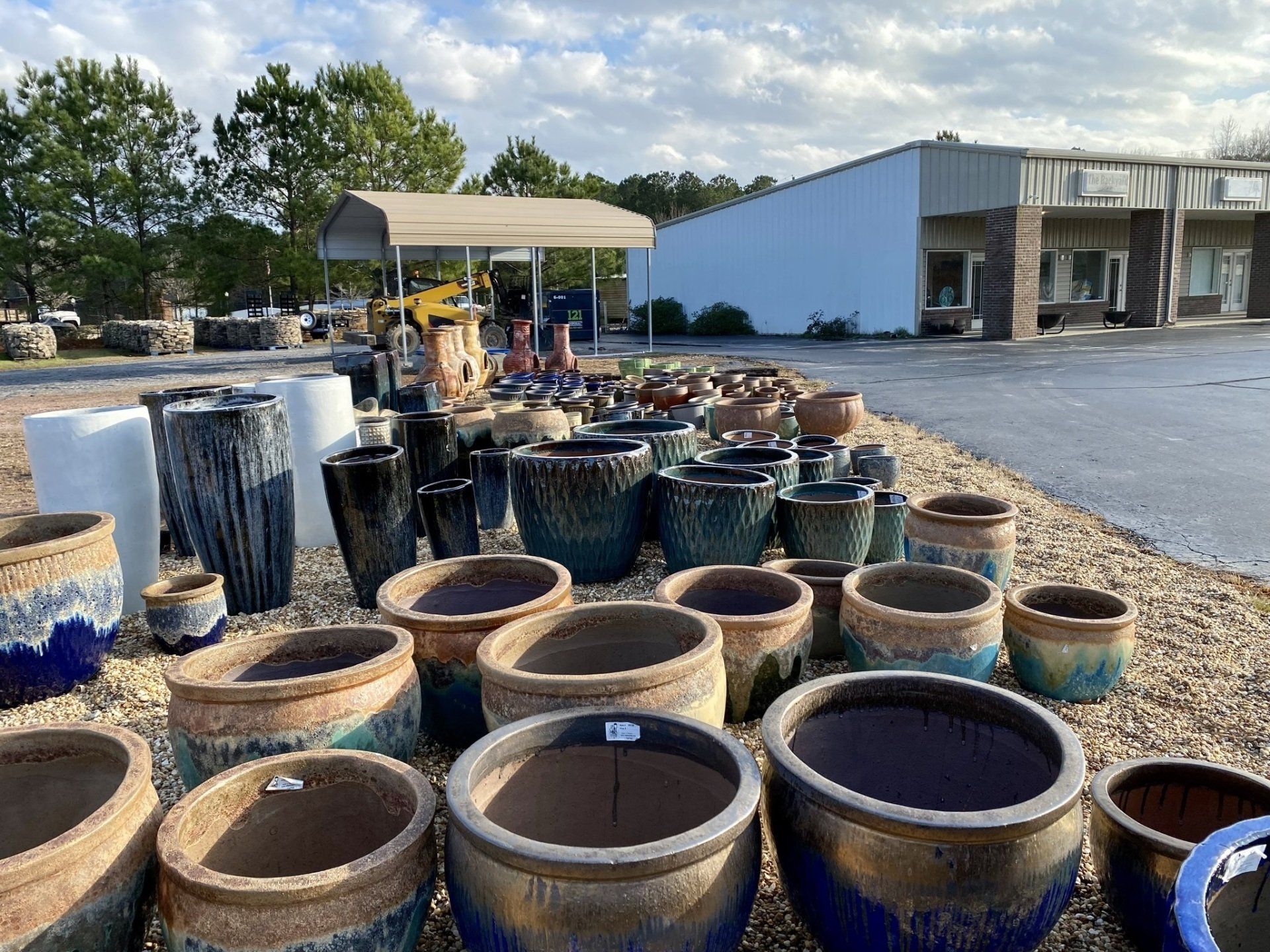 A bunch of pots are sitting on the ground in front of a building.