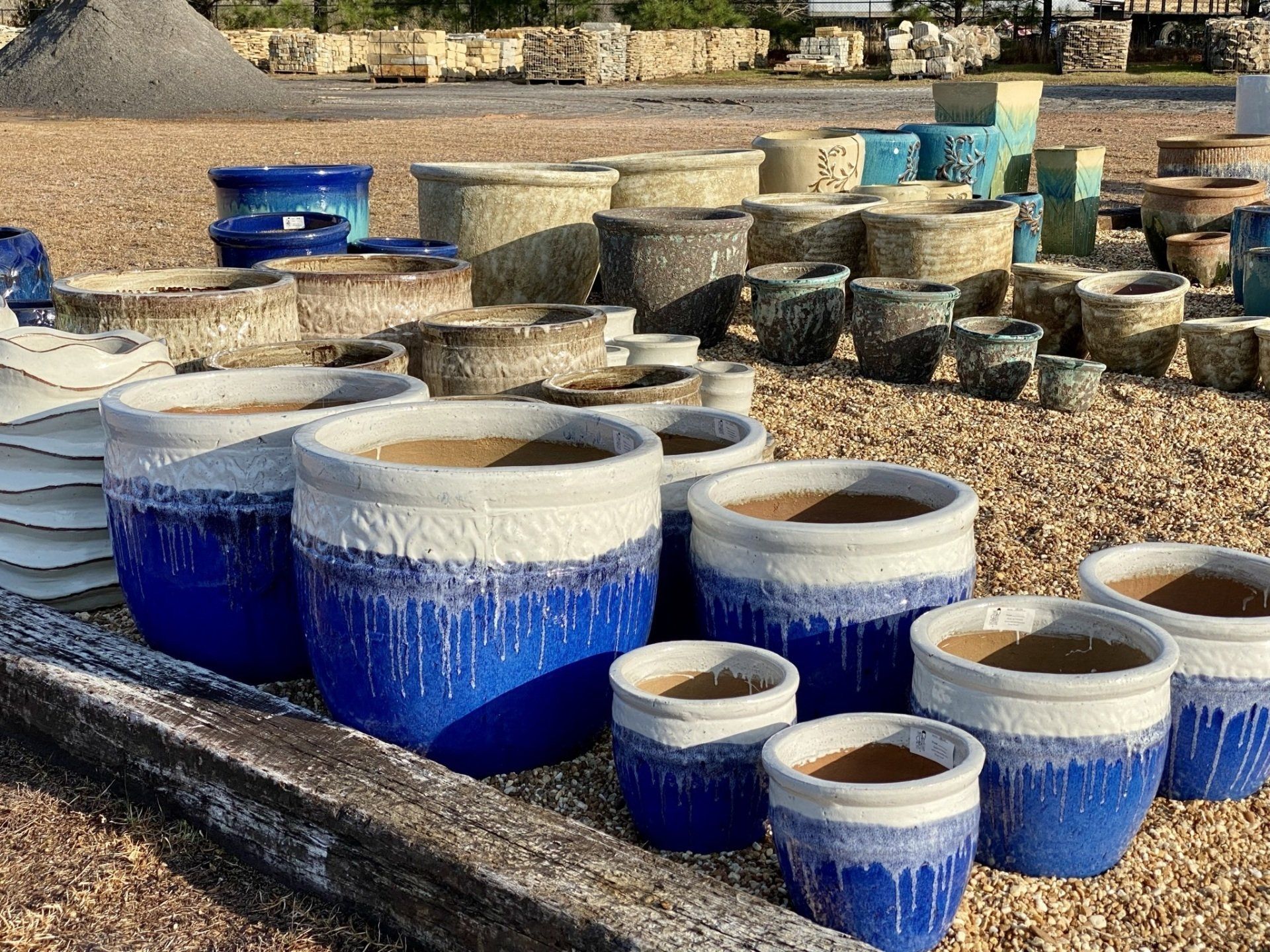 Collection of blue and white glazed ceramic planters displayed outdoors.