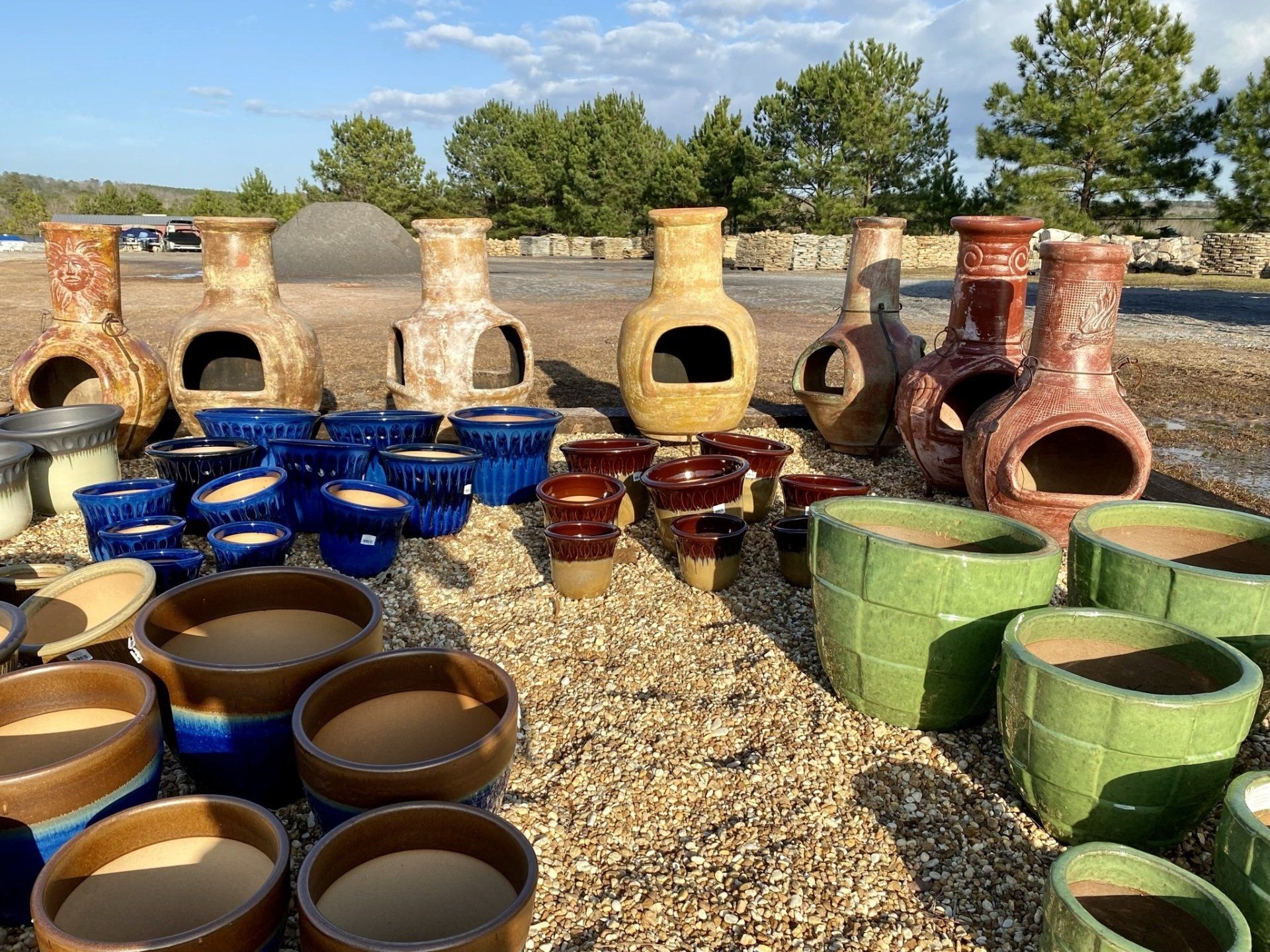 A bunch of pots and vases are sitting on a pile of gravel.