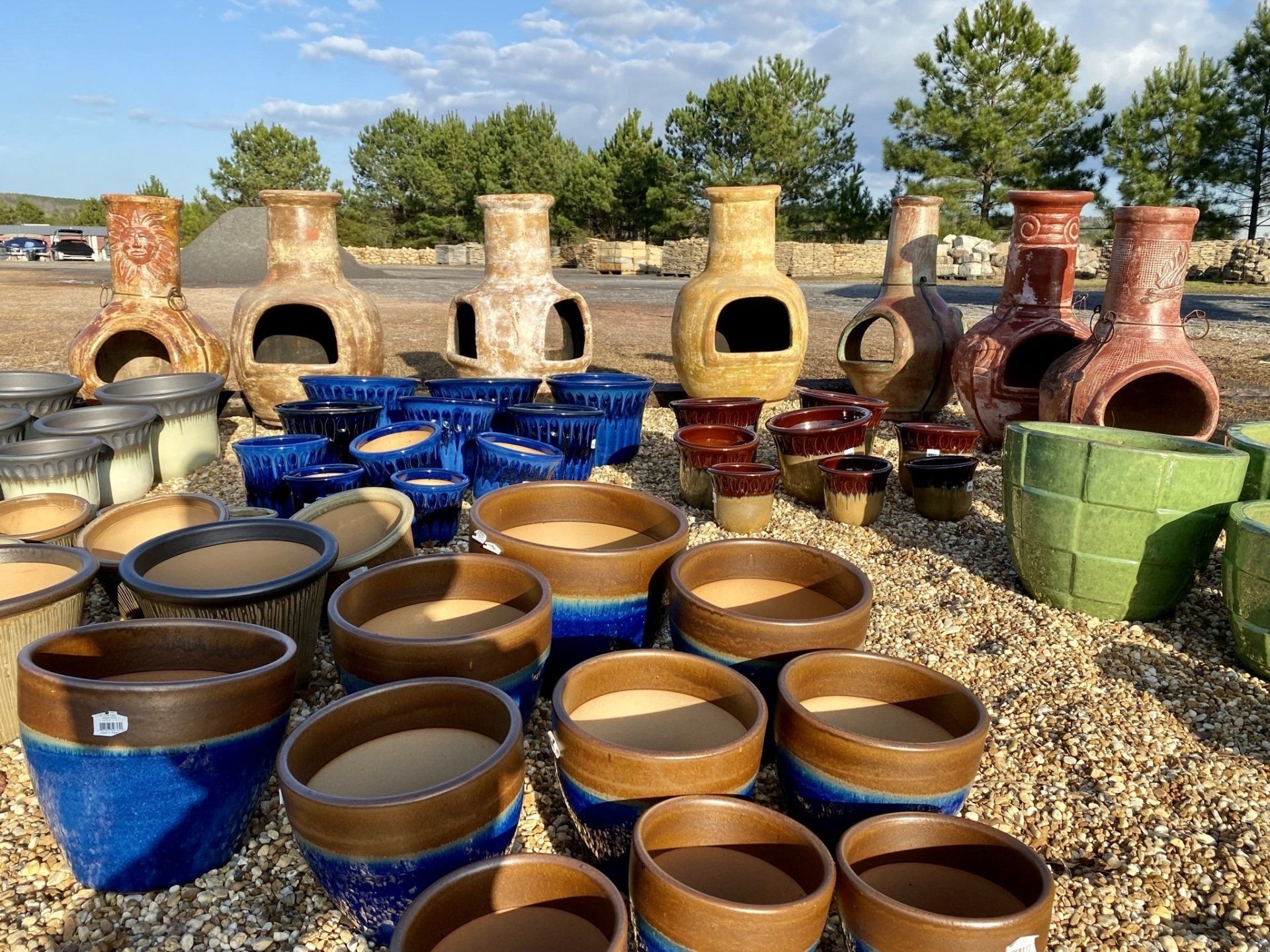 A bunch of pots and vases are sitting on a pile of gravel.