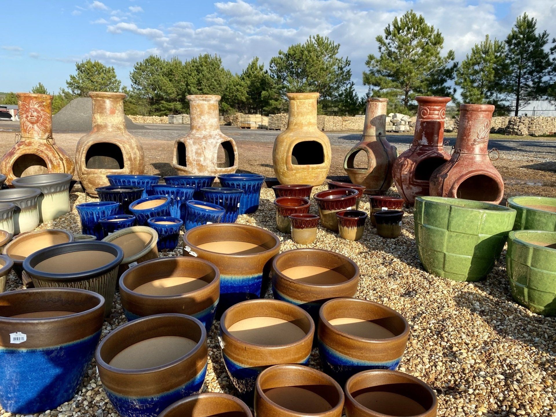 A bunch of pots and vases are sitting on a pile of gravel.