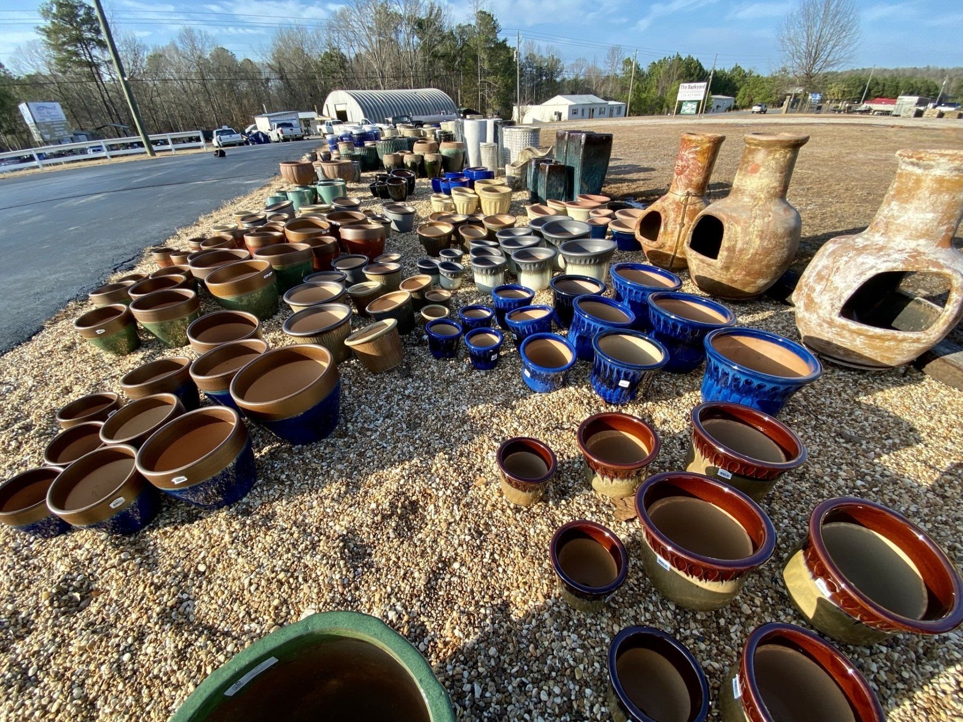 A bunch of pots and vases are sitting on a pile of gravel.